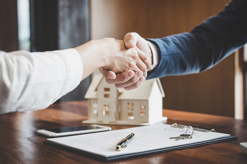 Mann und Frau geben sich die Hände nach einem erfolgreichen Verkauf einer Immobilie.